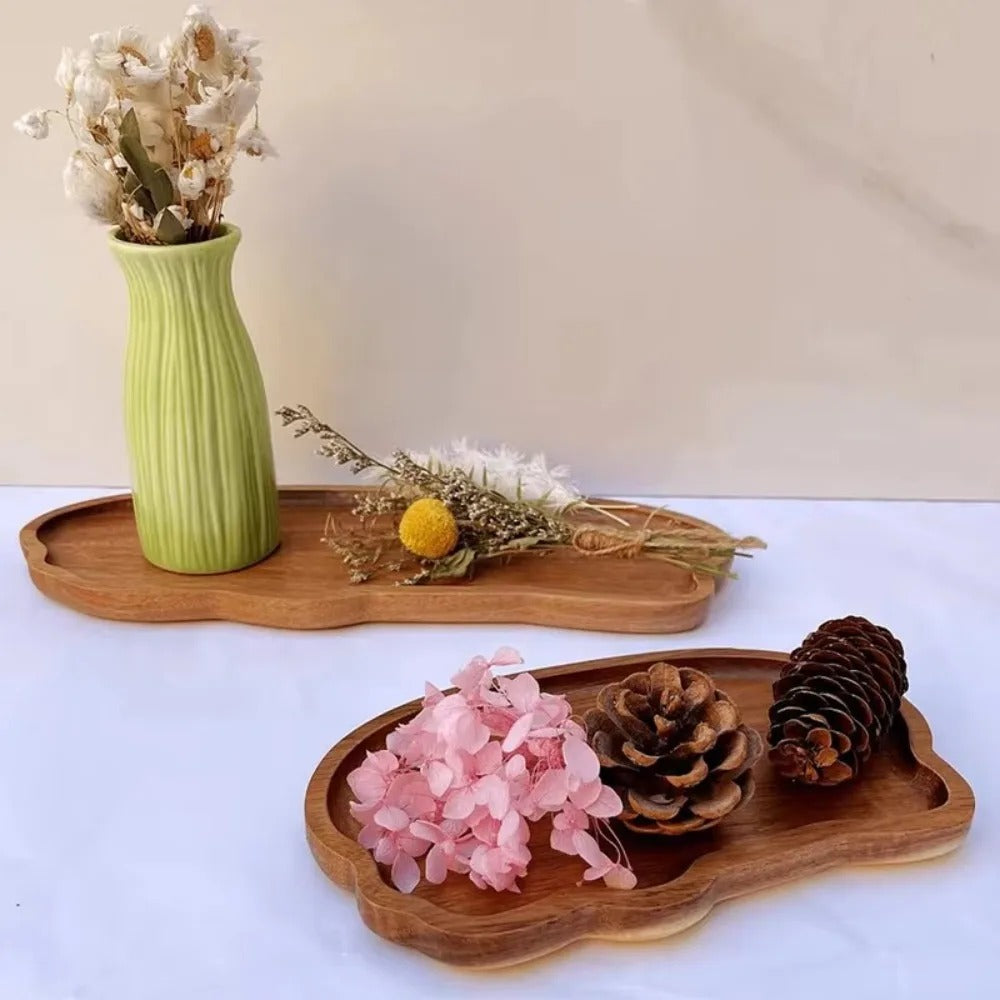Plateaux en bois d'acacia utilisés comme supports décoratifs avec fleurs séchées et objets de décoration.